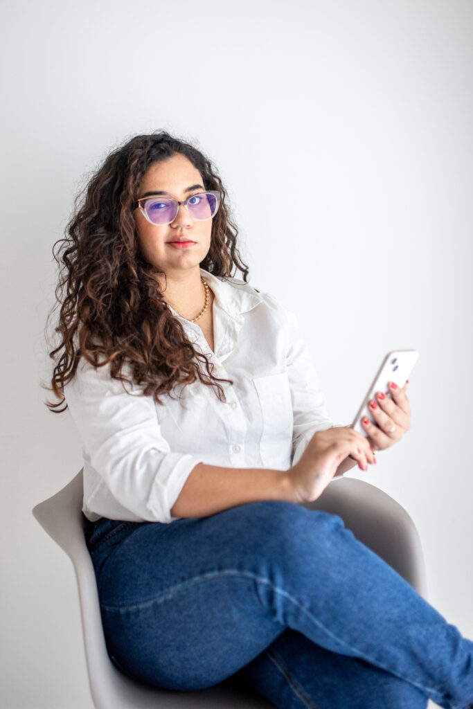 Marcella Pecly, nutricionista infantil, sentada com o celular na mão
